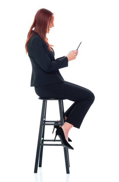 白人年轻女商人坐在白色背景前穿着商务装，使用手机图片下载