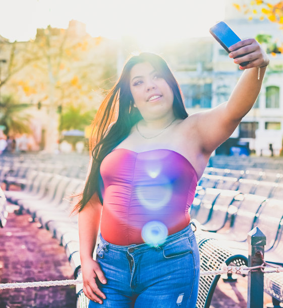 一个穿着筒状上衣的拉丁女孩在户外用手机图片下载