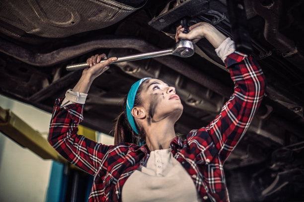 美丽的女机修工在修车厂修车。图片下载