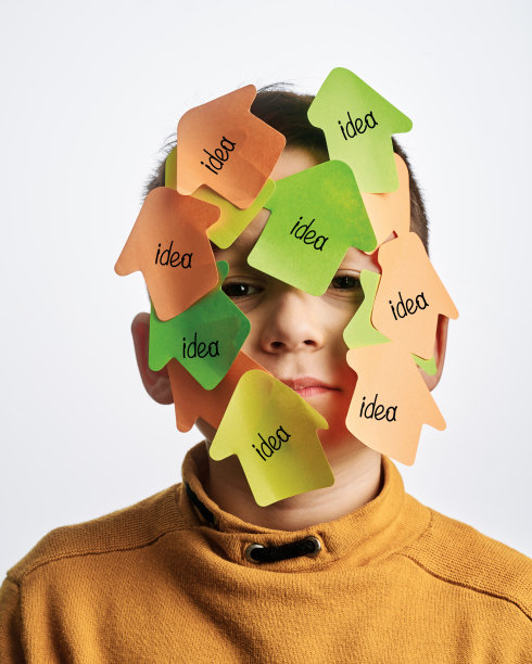 可爱的孩子在白色的背景。他的脸上有不干胶笔记。图片下载