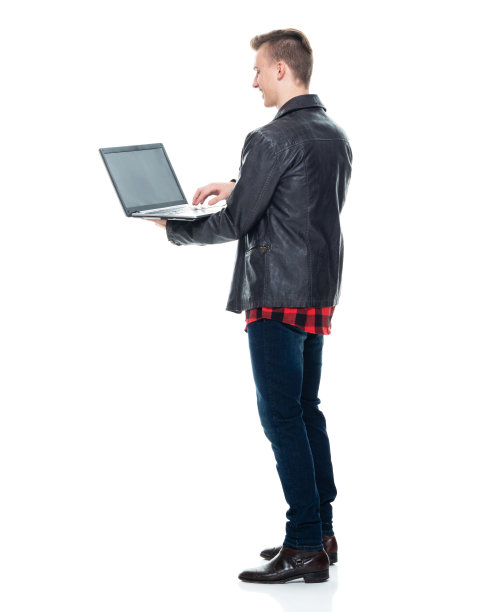 白人男孩穿着牛仔裤站在白色背景下使用笔记本电脑图片下载