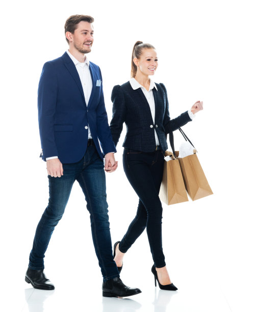 白人女性购物狂穿着商务休闲装，拿着购物袋走在白色背景前图片下载
