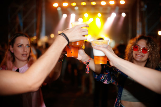 在音乐节上，欢乐的朋友们举起啤酒杯图片下载