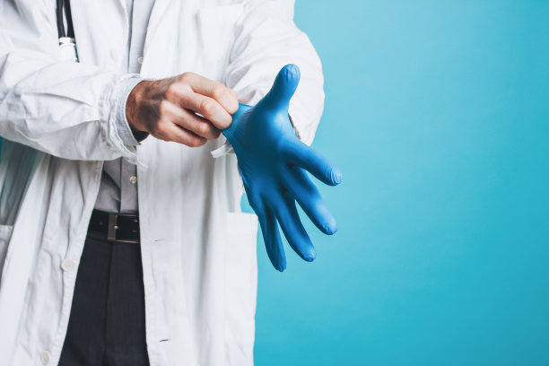 作物照片的男人医生在白大褂穿上橡胶医疗手套隔离在蓝色的背景图片下载