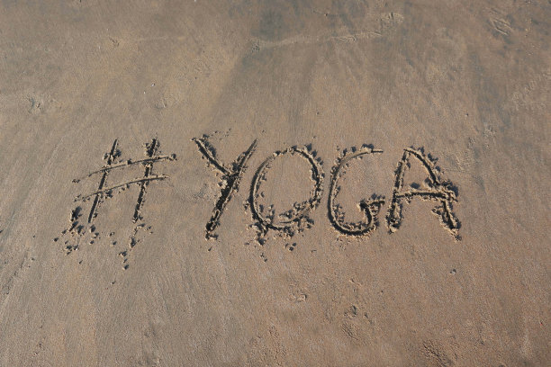 图片的标签标签写在阳光明媚的海滩上，瑜伽的单词写在海边的沙子，帕洛伦海滩，印度果阿，概念社交媒体照片的手写在金色的沙子与现代标签前缀图片下载