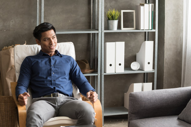 年轻的亚洲男子坐在窗边欣赏摩天大楼图片下载