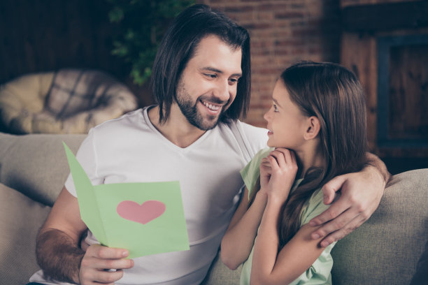 照片的小漂亮有趣多情的女士英俊的爸爸坐在舒适的沙发拥抱抱着生日卡片读问候的话祝福从亲戚度假房子房间室内图片下载