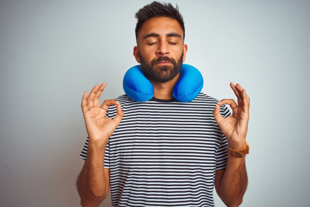 年轻的印度游客戴着颈枕在白色背景下冥想图片下载