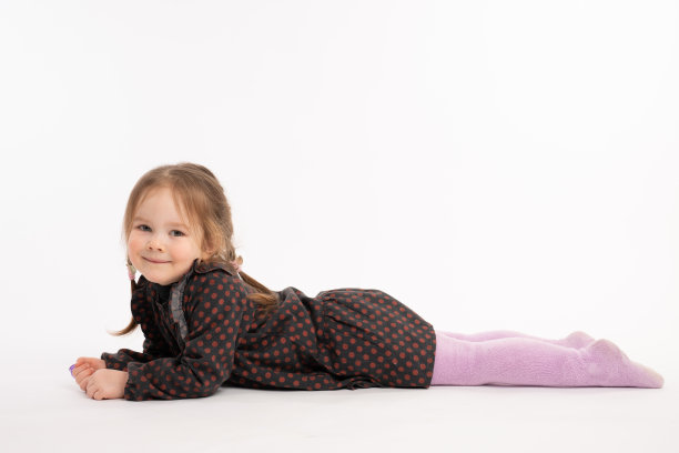 看着镜头的有趣女孩，红发女孩躺在白色背景的地上图片下载