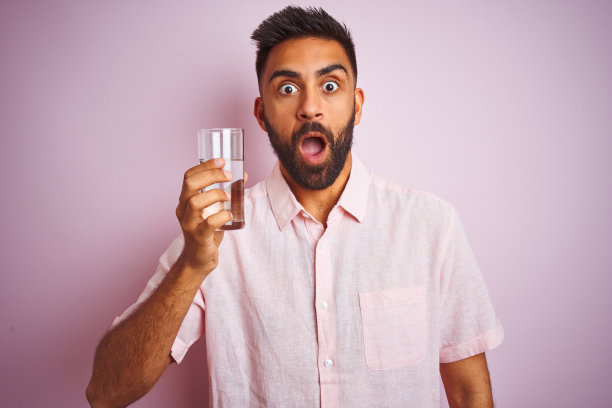 喝水的年轻印度男子，面带惊讶表情图片下载