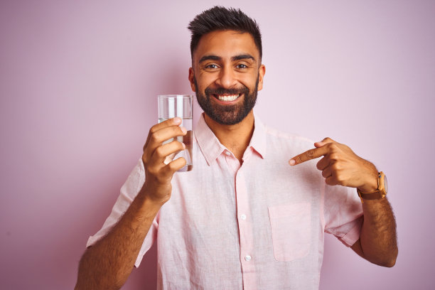 惊讶地指着自己的喝水的年轻印度男人图片下载