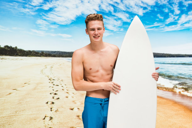 白人男性在自然面前谁在海滩上穿着泳衣和使用冲浪板图片下载