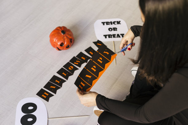 一个年轻女子在做万圣节花环。创意DIY。家居装饰项目派对。万圣节工艺品灵感。图片下载