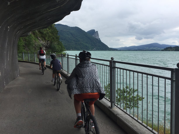 白种人家庭-父亲和两个儿子在水的边缘附近的绿松石湖在奥地利阿尔卑斯山在阴天的夏天图片下载