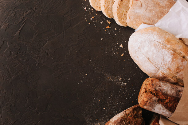 石桌上摆放着各种酥脆的面包和小圆面包，面包片上点缀着新鲜出炉的手工黑麦面包片。俯视图，复制空间图片下载