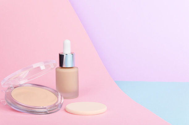 面部皮肤矫正化妆品浅紫色，粉色和蓝色粉彩背景。液体遮瑕膏，面部粉末，海绵成分与文字。女性化妆品空白背景。图片下载