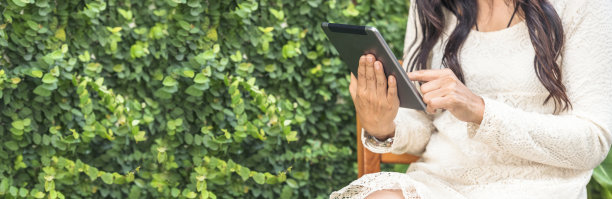 亚洲女人在智能手机上使用ipad在网上购物，面带微笑。快乐的亚洲女人拿着手机，查看网上购物网站的邮件，阅读博客、社交媒体文章图片下载