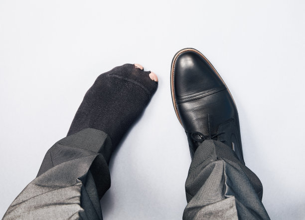 失业男子概念图：一只脚穿皮鞋，另一只脚穿破袜子图片下载