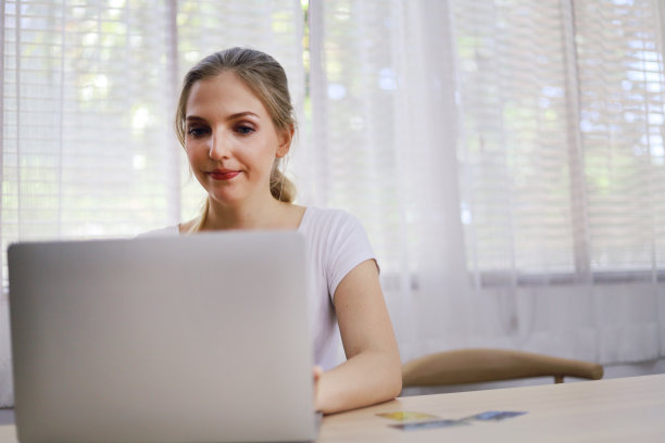美丽的年轻女子微笑肖像和网上购物的笔记本电脑在家里在假日周末。图片下载