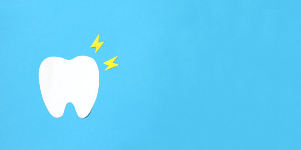 蓝色背景上的纸牙模型和黄色闪电，牙痛概念图片下载