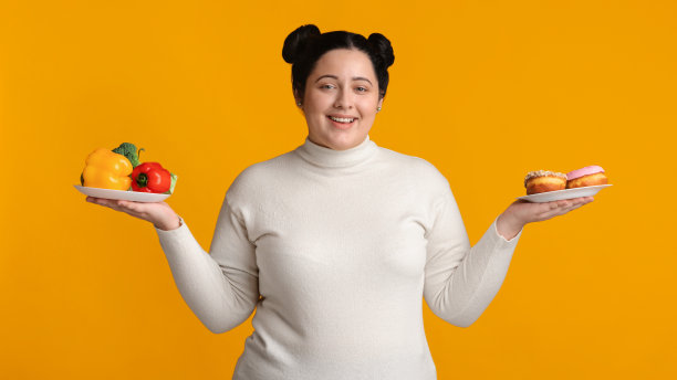 拿着新鲜蔬菜和甜甜圈盘子的微笑的加大码女孩图片下载