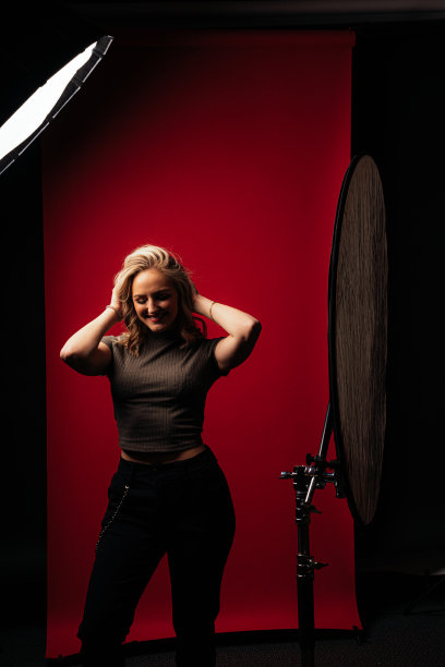 广角背后的场景照片年轻美丽的金发白人成年女性时尚模特在休闲服装摆姿势在明亮的红色工作室无缝背景与复制空间图片下载