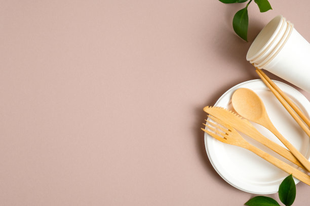 竹制餐具，配有可生物降解的纸盒、纸杯和盘子，放在木桌上。生态商店横幅模板与环保餐具和绿色树叶。零浪费，无塑料的概念。图片下载