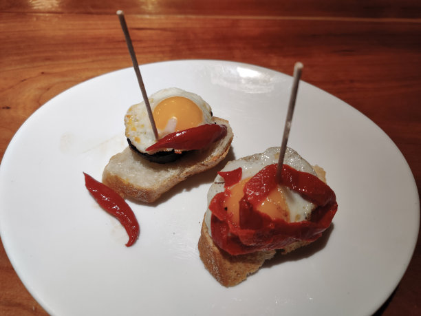 两道小吃，黑布丁，鹌鹑蛋和红辣椒放在白盘子里图片下载