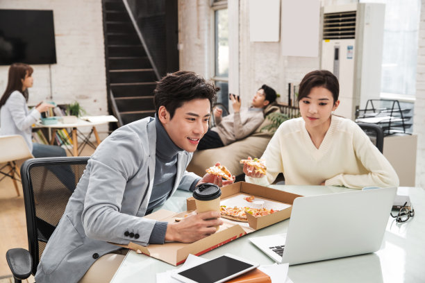 青年商务人士边吃披萨边工作图片下载