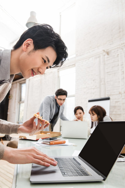 青年商务男士边吃披萨边工作图片下载