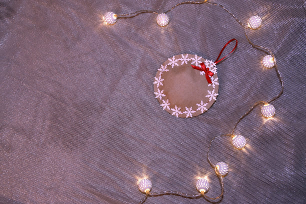 一个用雪花装饰的由牛皮纸制成的圣诞装饰球，周围是一个由白色球组成的花环。圣诞概念，工艺品，装饰。图片下载