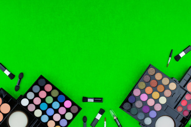 绿色背景上的专业彩色化妆品和刷子图片下载