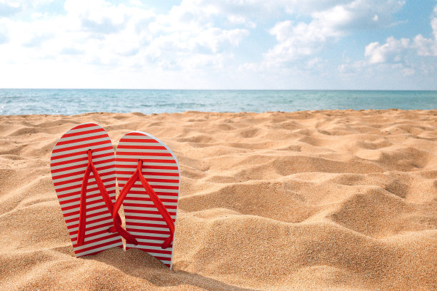 在海边的沙滩上，穿着黄色的沙滩上的红拖鞋，暑假图片下载