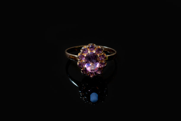 美丽的金色戒指与紫色宝石孤立在黑色背景图片下载