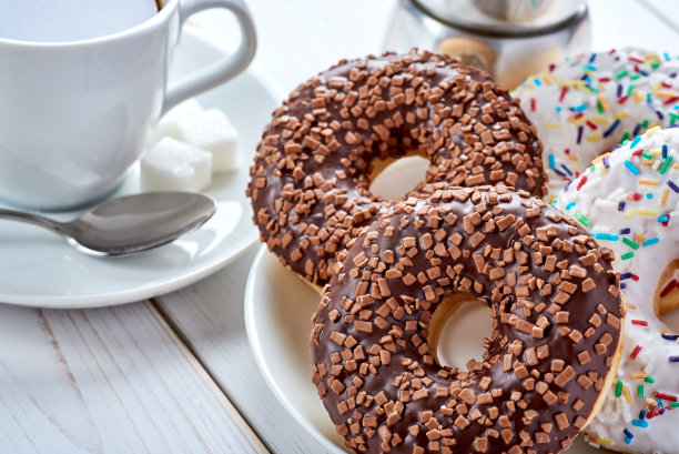 甜早餐或零食的特写照片。巧克力甜甜圈和一杯咖啡。白色木制桌面与文字空间。图片下载