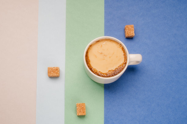 白杯子里的一杯牛奶咖啡，彩色背景是黑巧克力图片下载