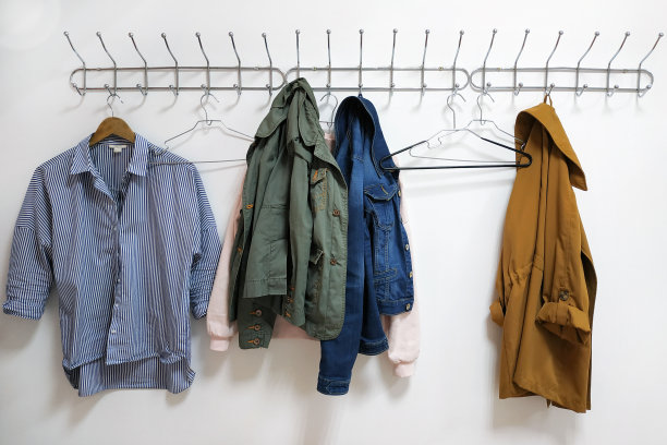 一件衬衫、夹克和一个衣架挂在金属的墙上衣架上。图片下载