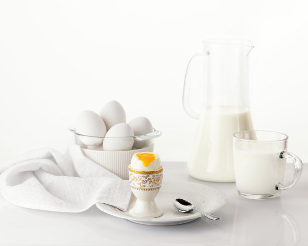 白色盘子上放一只煮熟的鸡蛋，上面有金色和白色的复活节彩蛋图片下载