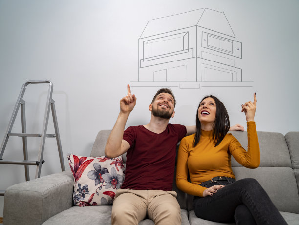 男人和女人坐在沙发上梦想着新家，梦想成真了图片下载