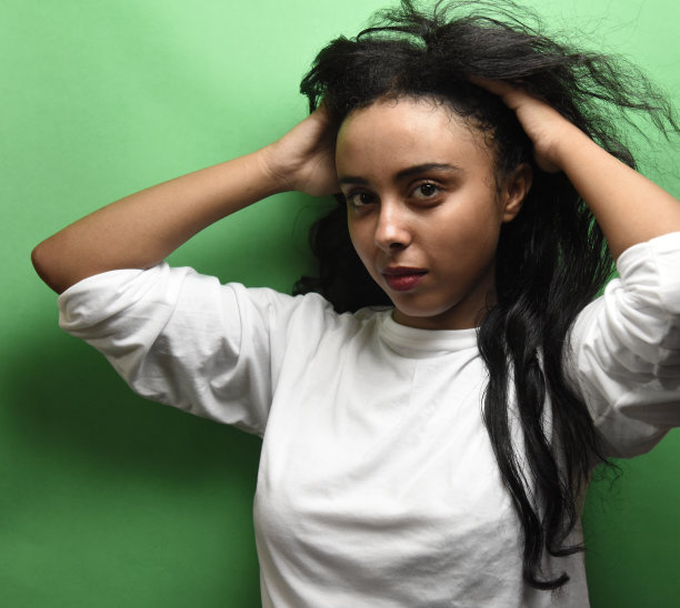 有着一头黑发的中东年轻女子。室内照片的奇妙女性模特在绿色的背景。图片下载