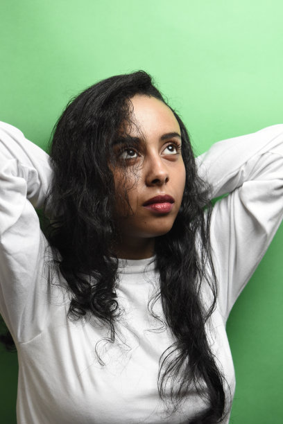 有着一头黑发的中东年轻女子。室内照片的奇妙女性模特在绿色的背景。图片下载