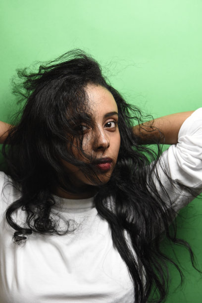 有着一头黑发的中东年轻女子。室内照片的奇妙女性模特在绿色的背景。图片下载