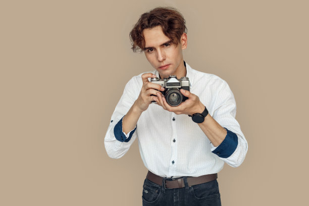 自由泳。时尚的摄影师孤立地站在灰色上，用相机集中拍照图片下载