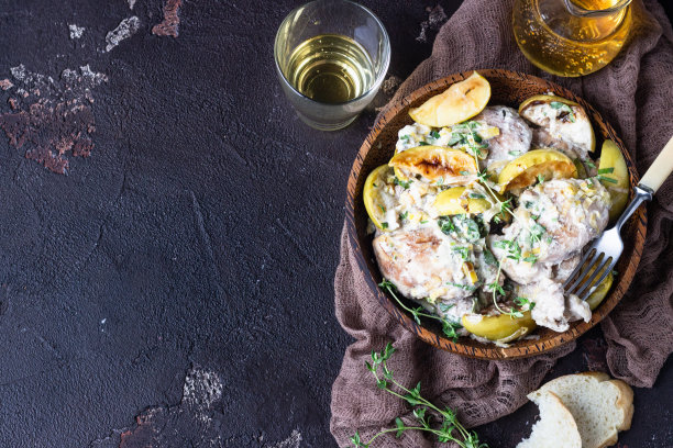 在深褐色的木桌上，烤鸡腿，配上苹果和苹果酒。晚餐食谱。舒适的食物。图片下载
