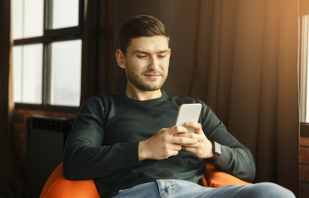 学生在室内豆袋椅上用手机发短信图片下载