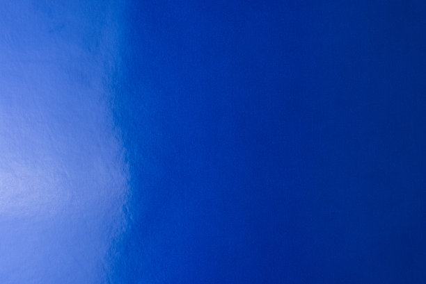 蓝色背景的真实，有光泽的彩色纸，被柔和的光从左边照亮。图片下载