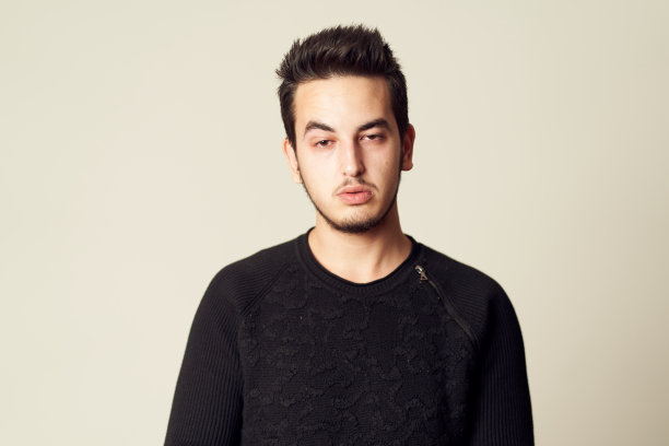 年轻男子在演播室里用休闲装表现疲倦的表情。昏昏欲睡的年轻男性看着镜头图片下载