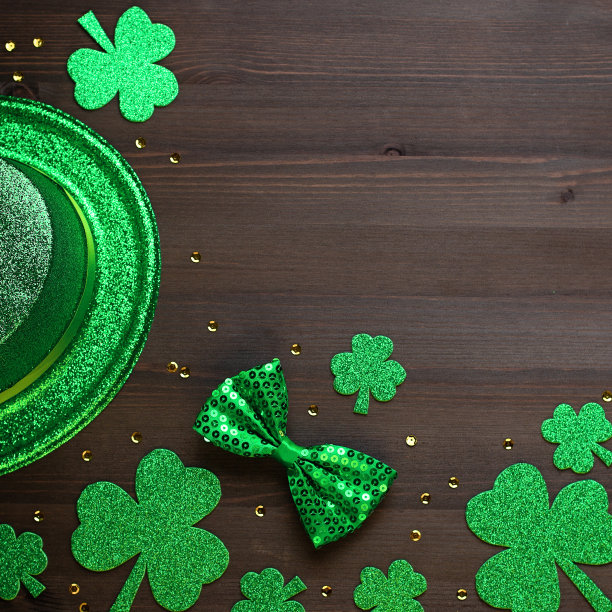 圣帕特里克节贺卡，带有传统符号，三叶草，绿色服装。绿色的帽子，领结，圣帕特里克节三叶草，金色的纸屑在深色的木制背景，复制空间图片下载