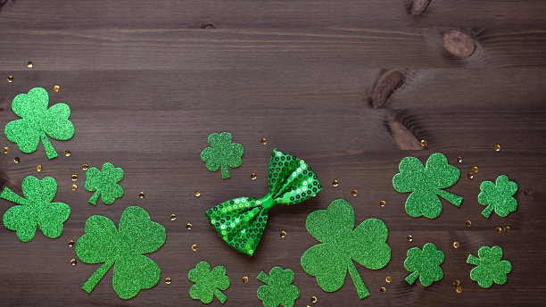 圣帕特里克节贺卡，带有传统符号，三叶草，绿色服装。绿色的帽子，领结，圣帕特里克节三叶草，金色的纸屑在深色的木制背景，复制空间图片下载