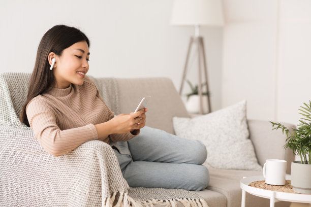 休闲活动：女孩在家里的沙发上听音乐图片下载